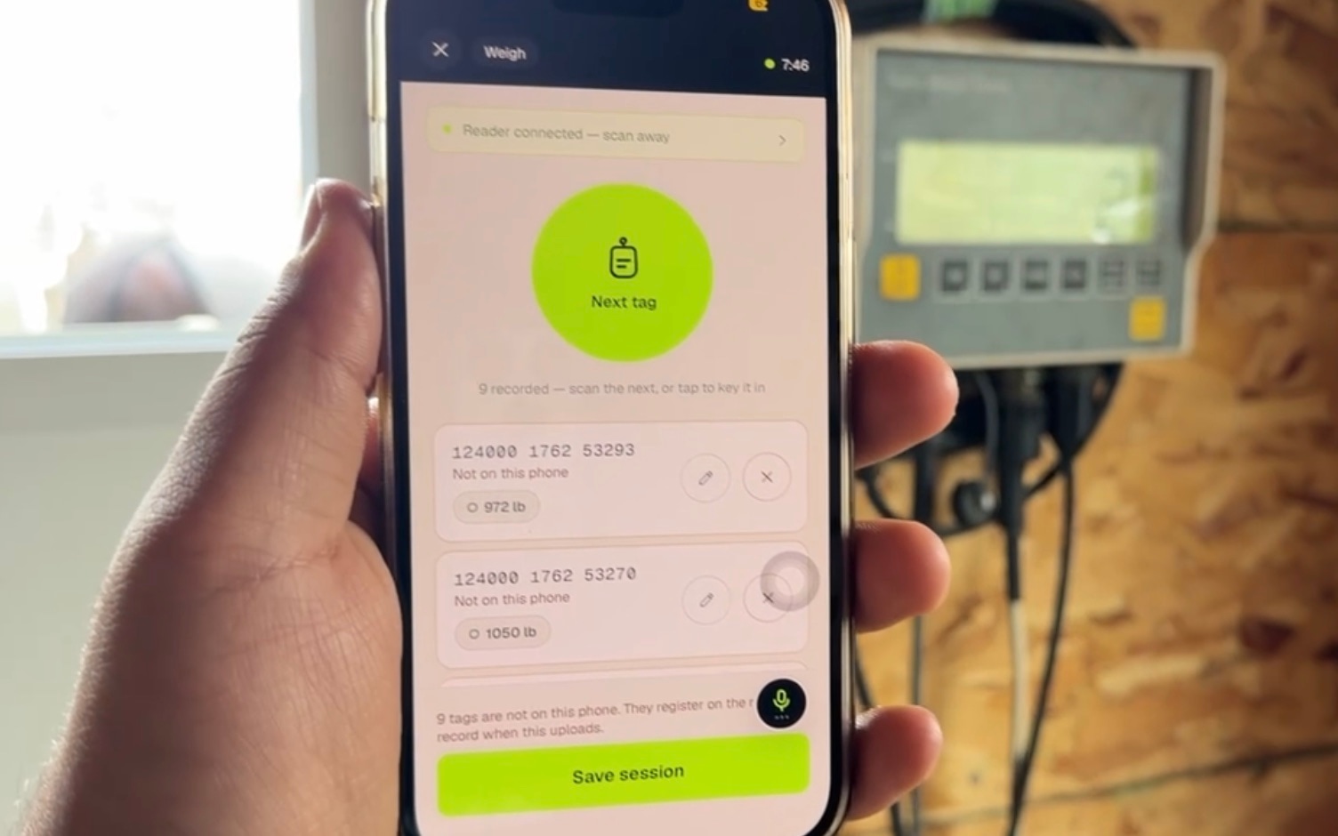 A rancher holding a phone showing Agrivanna's weigh screen beside a scale head indicator